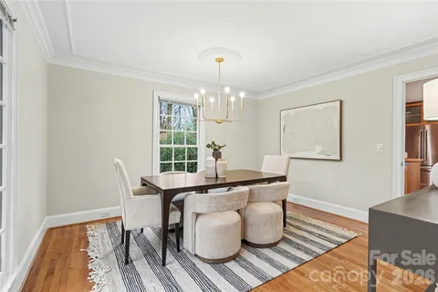 a dining room with wooden floor a chandelier a wooden table and chairs