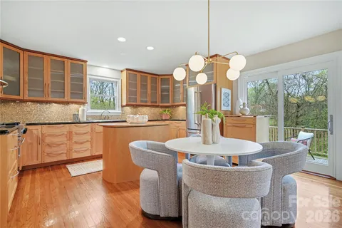 a dining room with wooden floor a chandelier a glass table and chairs