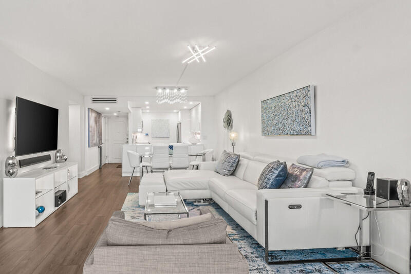 a living room with furniture a flat screen tv and a chandelier