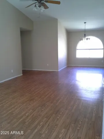 an empty room with wooden floor and chandelier fan