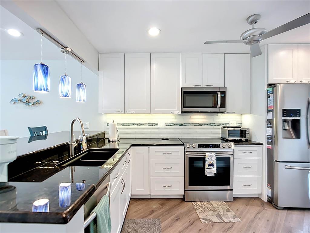 1508 Pelican Cove Road, Unit GR232 Sarasota, FL 34231 - Photo 8 of 54 a kitchen with stainless steel appliances a stove sink microwave and cabinets