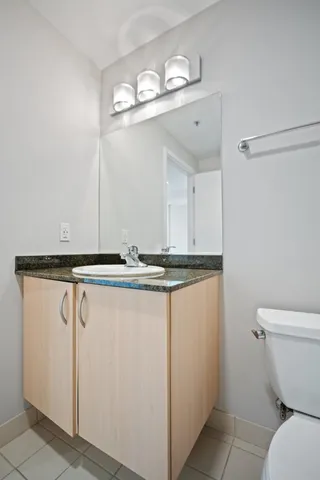 a bathroom with a granite countertop sink a toilet and mirror