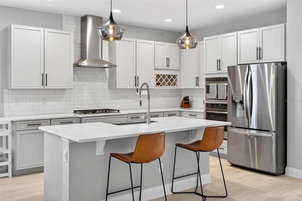 2139 Bay Line Road Oakland, FL 34787 - Photo 5 of 57 a kitchen with stainless steel appliances granite countertop a sink a stove a refrigerator and island with wooden floor