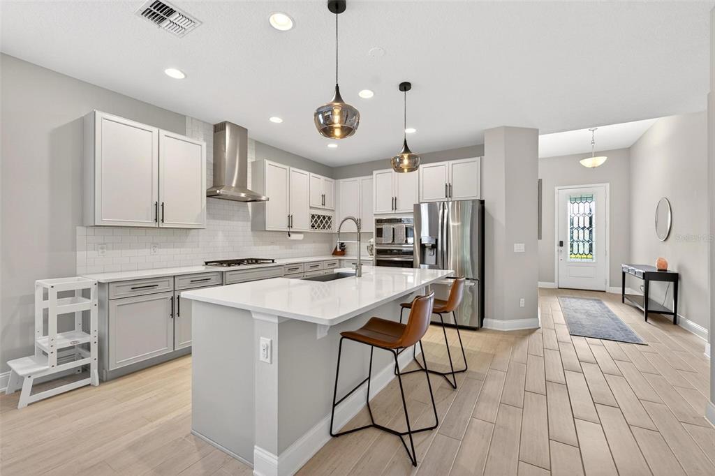 2139 Bay Line Road Oakland, FL 34787 - Photo 8 of 57 a kitchen with stainless steel appliances kitchen island granite countertop a stove a sink a refrigerator and white cabinets with wooden floor