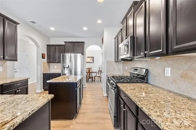 a kitchen with stainless steel appliances granite countertop a stove refrigerator and cabinets