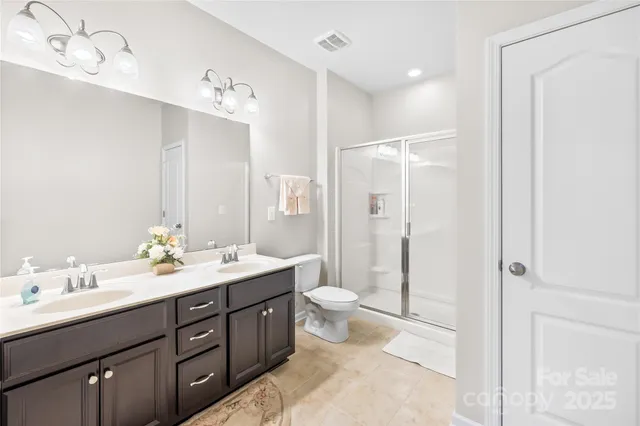 a spacious bathroom with a double vanity sink toilet mirror and shower