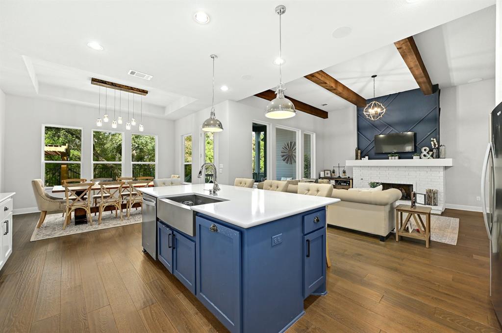 629 Germander Road Leander, TX 78641 - Photo 12 of 32 An open concept design blends living, dining, and kitchen areas, featuring rich wood floors and exposed ceiling beams.