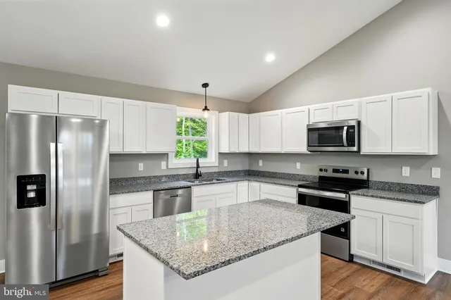 a kitchen with stainless steel appliances granite countertop a refrigerator a sink a stove a microwave and cabinets