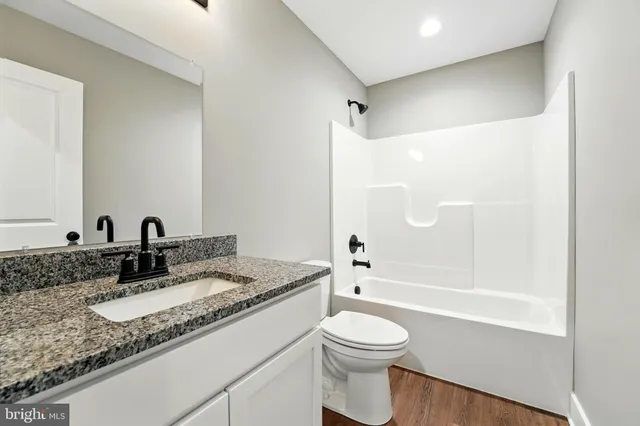 a bathroom with a granite countertop sink a toilet and shower