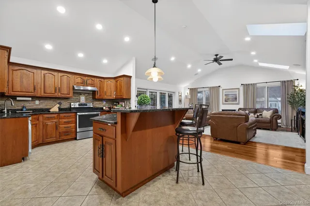 a kitchen with stainless steel appliances granite countertop a refrigerator and a view of living room