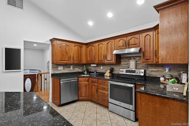 a kitchen with stainless steel appliances granite countertop wooden cabinets a stove top oven a sink and dishwasher