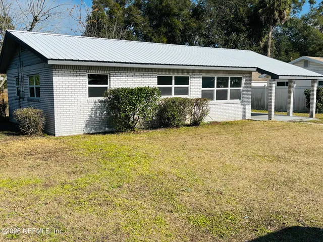 a front view of house with yard and trees in the background