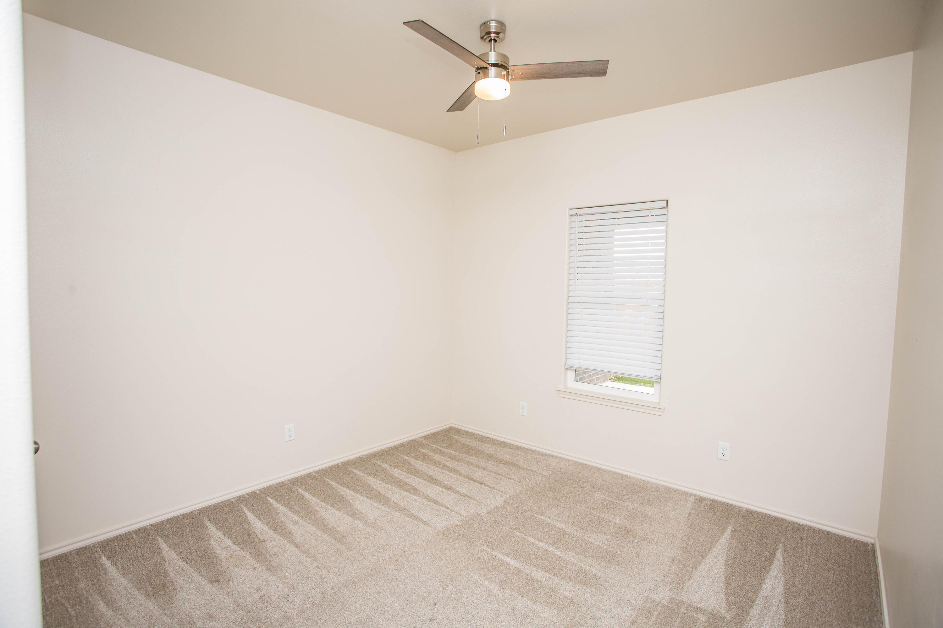 5613 Kemper Street Lubbock, TX 79416 - Photo 22 of 35 an empty room with a window and ceiling fan