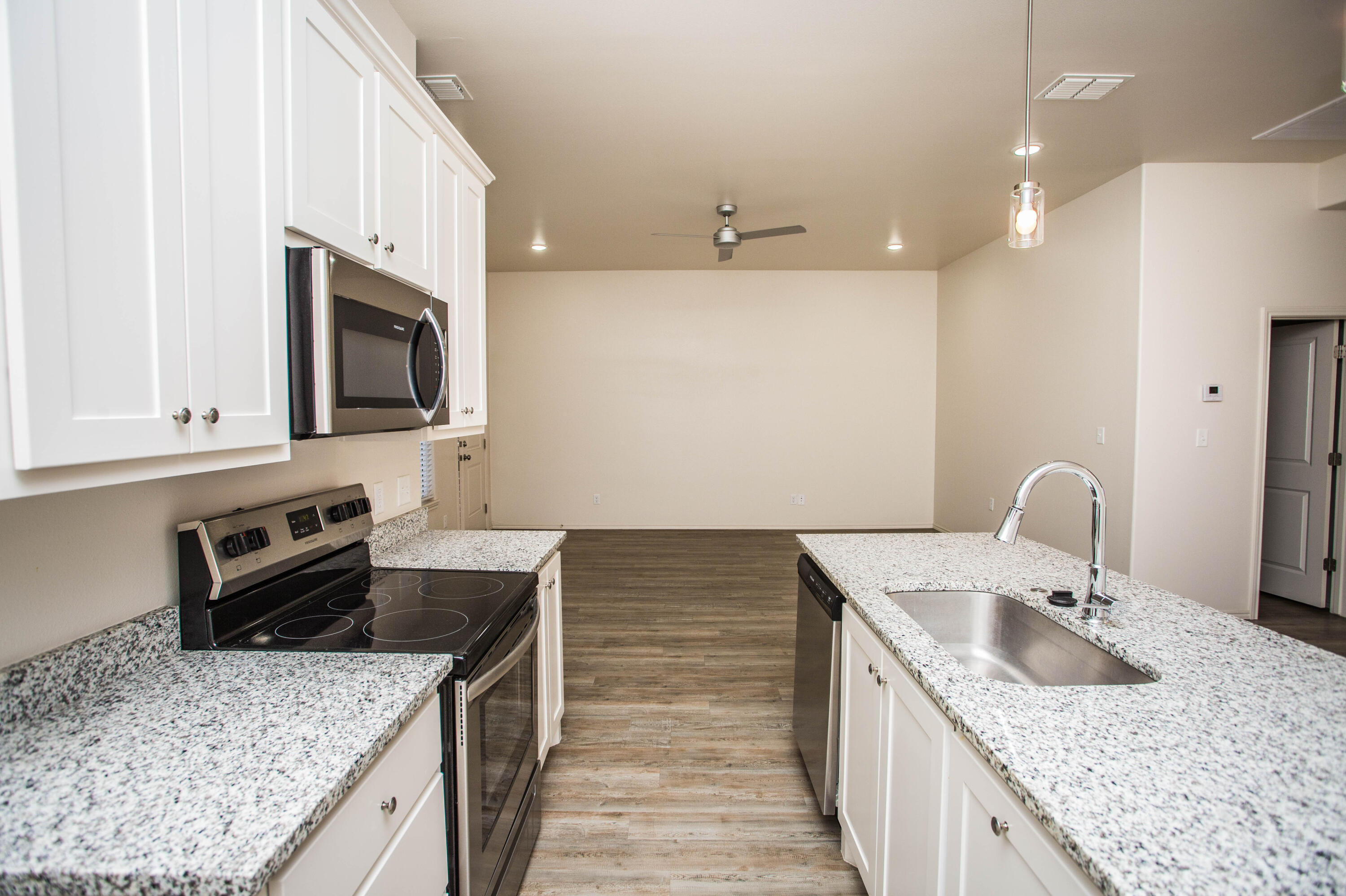 5613 Kemper Street Lubbock, TX 79416 - Photo 25 of 35 a kitchen with granite countertop a sink and a stove top oven with wooden floor