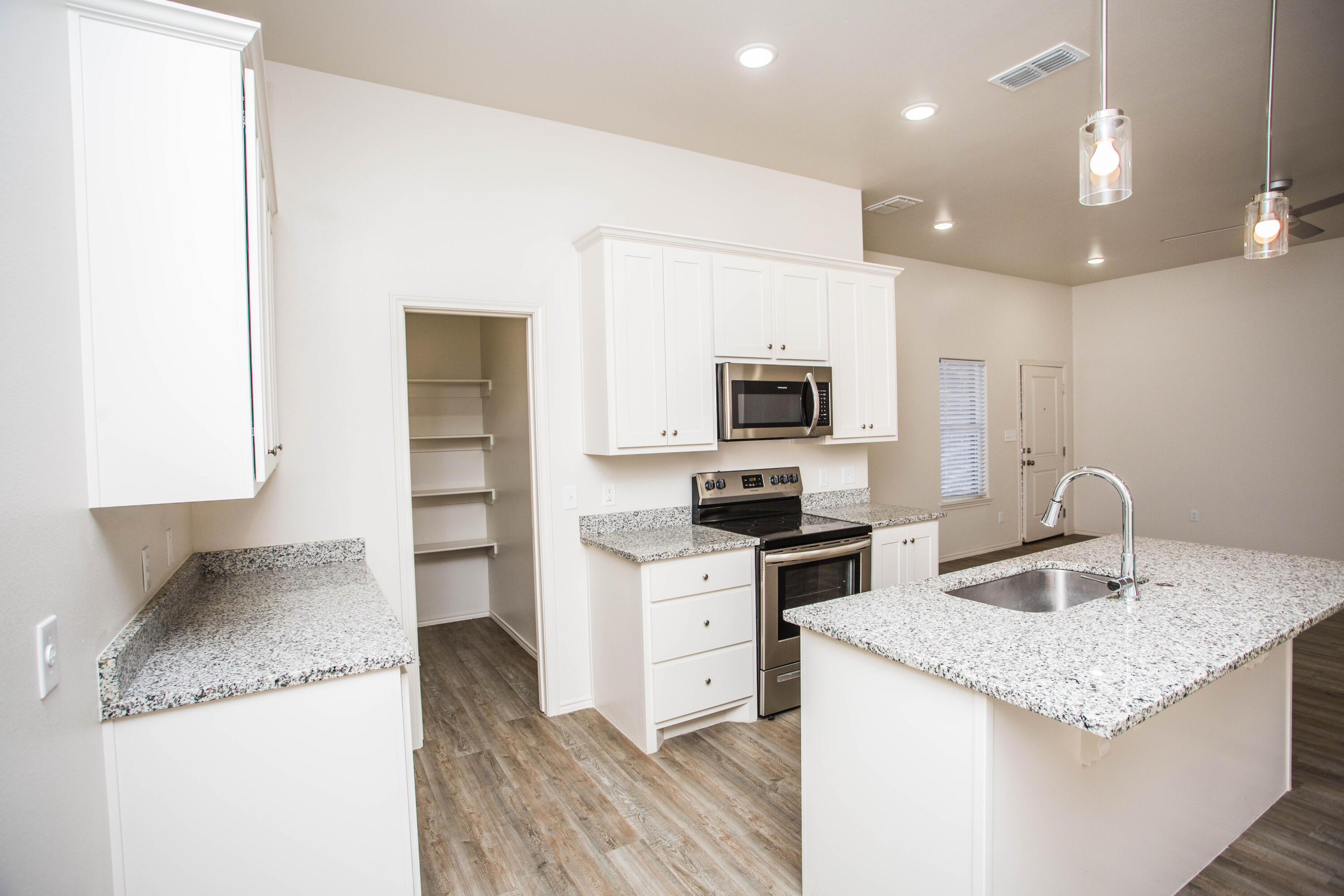 5613 Kemper Street Lubbock, TX 79416 - Photo 5 of 35 a kitchen with granite countertop a sink and a stove top oven with wooden floor