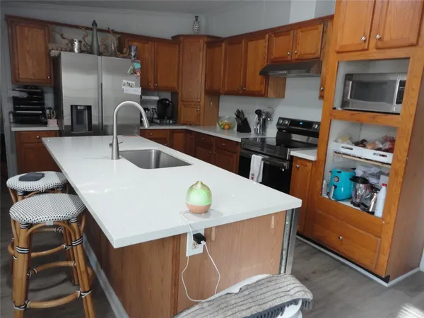a kitchen with stainless steel appliances kitchen island a table chairs and a refrigerator