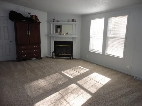an empty room with windows and fireplace