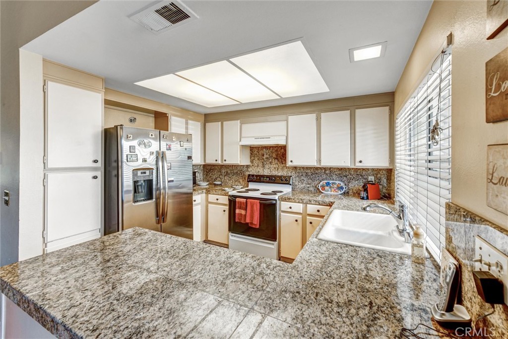 a kitchen with stainless steel appliances granite countertop a refrigerator sink and stove