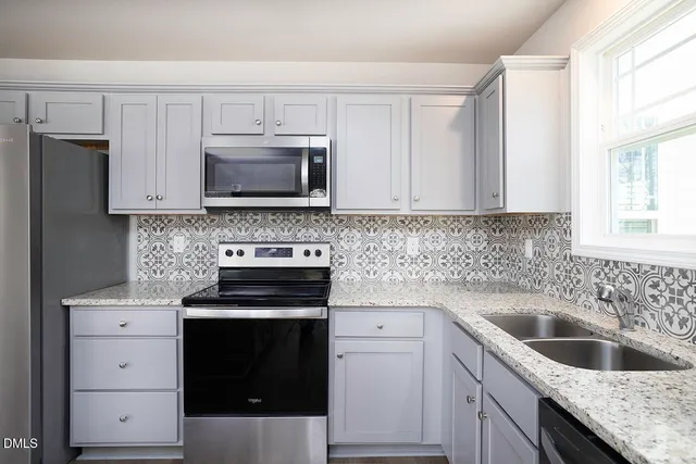 a kitchen with stainless steel appliances granite countertop a refrigerator stove microwave and sink