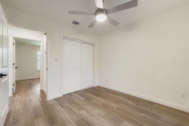 an empty room with wooden floor and ceiling fan
