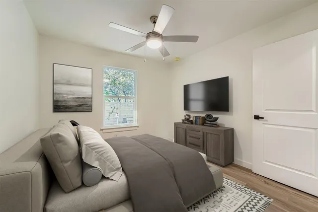 an empty room with wooden floor chandelier fan and windows
