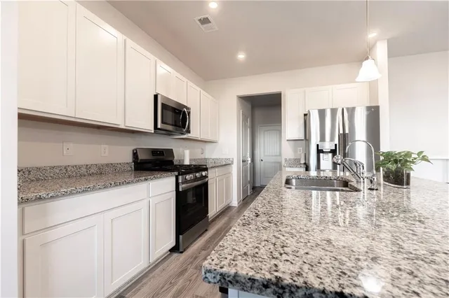 a living room with stainless steel appliances granite countertop a stove a sink and a microwave