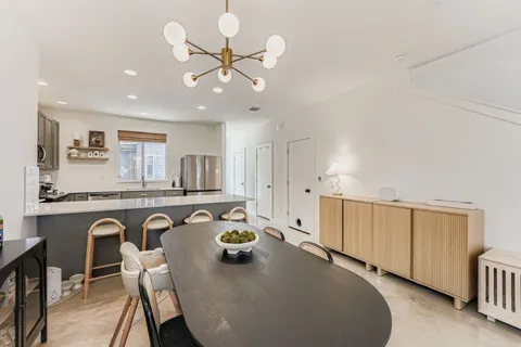 a kitchen with stainless steel appliances granite countertop a stove a sink a dining table and chairs with white cabinets