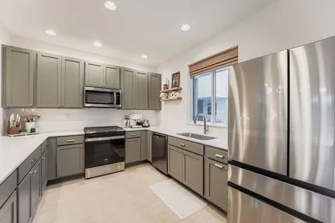 a kitchen with stainless steel appliances granite countertop a refrigerator stove sink and cabinets