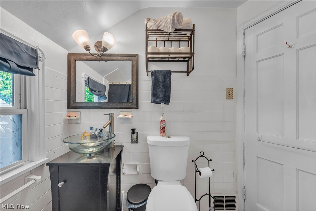 3962 Grosvenor Road South Euclid, OH 44118 - Photo 21 of 27 Bathroom featuring a glass vessel sink with a brushed nickel faucet, a dark wood-finish vanity with cabinet storage, a decorative wall mirror, and a two-light vanity fixture
