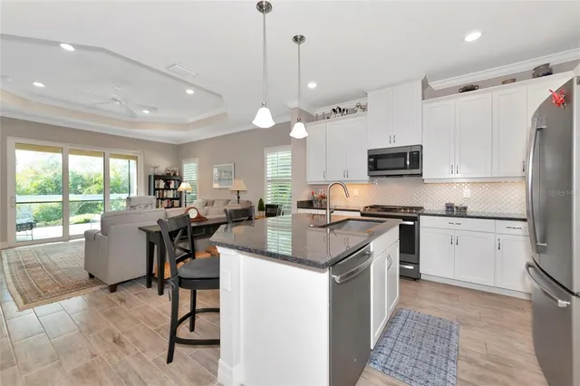 a kitchen with kitchen island a large counter top space a sink stainless steel appliances and cabinets