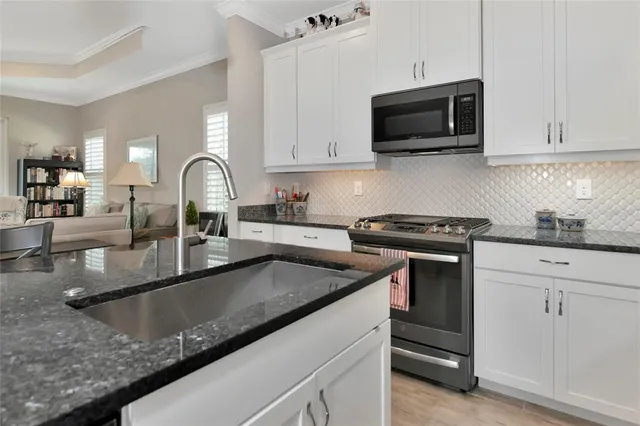 a kitchen with granite countertop a sink and a stove top oven with wooden floor