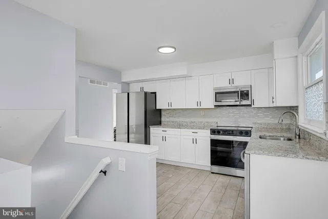 a kitchen with white cabinets and stainless steel appliances