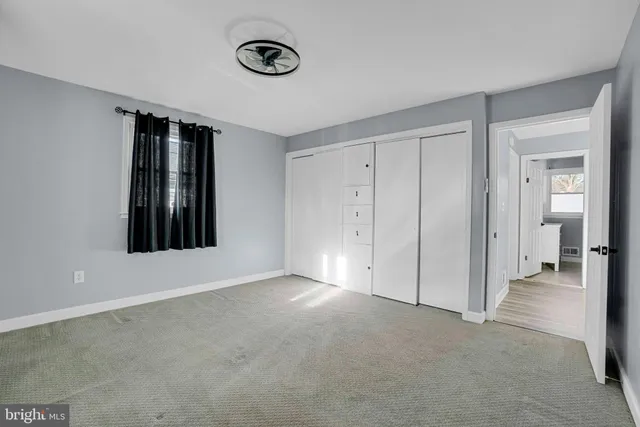 a view of an empty room with window and closet area