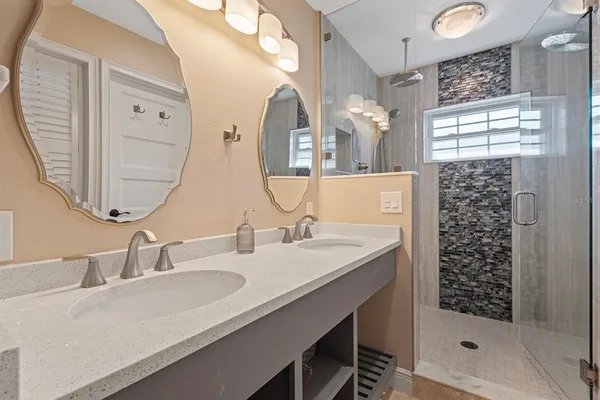 a bathroom with a double vanity sink mirror and shower