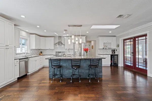 a kitchen with stainless steel appliances granite countertop a stove top oven a sink dishwasher a dining table and chairs with wooden floor