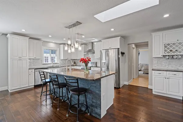 a kitchen with stainless steel appliances kitchen island granite countertop a refrigerator and a stove top oven