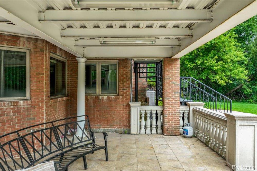 3543 Cedar Brook Drive Rochester, MI 48309 - Photo 87 of 99 Covered patio with a brick exterior, stone balustrades, wrought iron railings, and a concrete paver floor