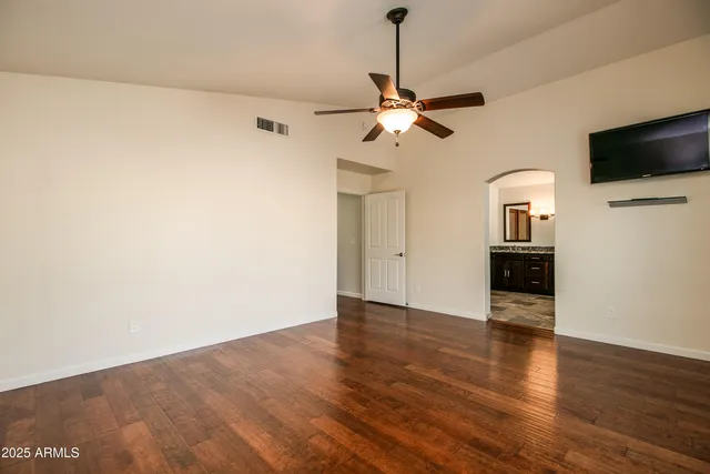 a view of a livingroom with wooden floor and a ceiling fan
