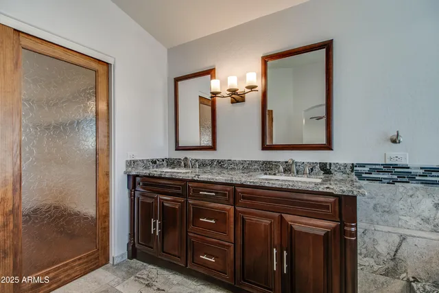 a bathroom with a granite countertop sink a mirror and a shower