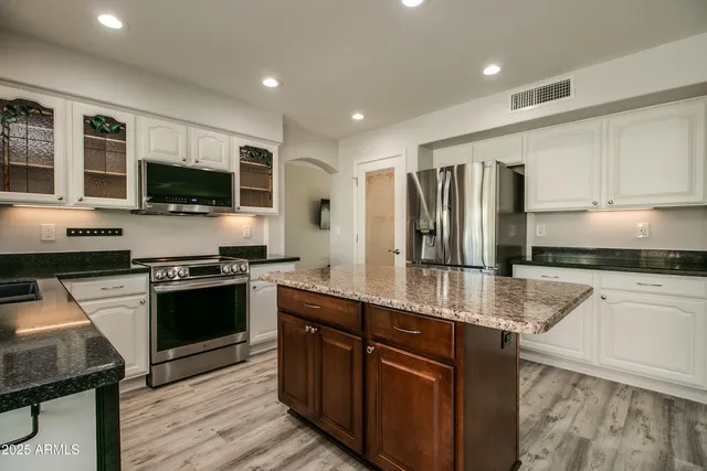 a kitchen with stainless steel appliances granite countertop a stove refrigerator and microwave