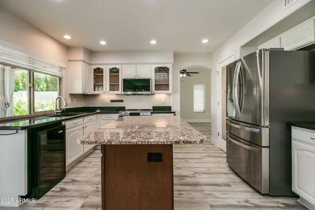 a kitchen with stainless steel appliances granite countertop a refrigerator a stove and a sink