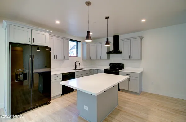a kitchen with stainless steel appliances a stove a refrigerator a sink and white cabinets