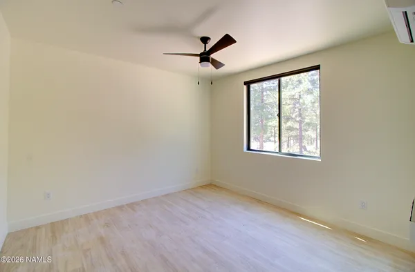 an empty room with wooden floor ceiling fan and windows