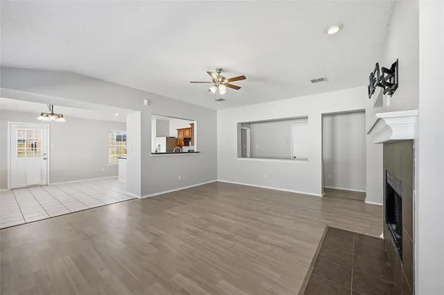a view of an empty room with a fireplace and a ceiling fan