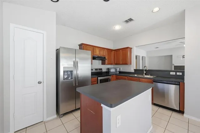a kitchen with stainless steel appliances granite countertop a refrigerator a sink a stove a microwave and island