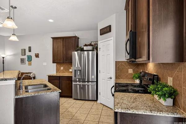a kitchen with stainless steel appliances granite countertop a refrigerator a stove a sink and a microwave