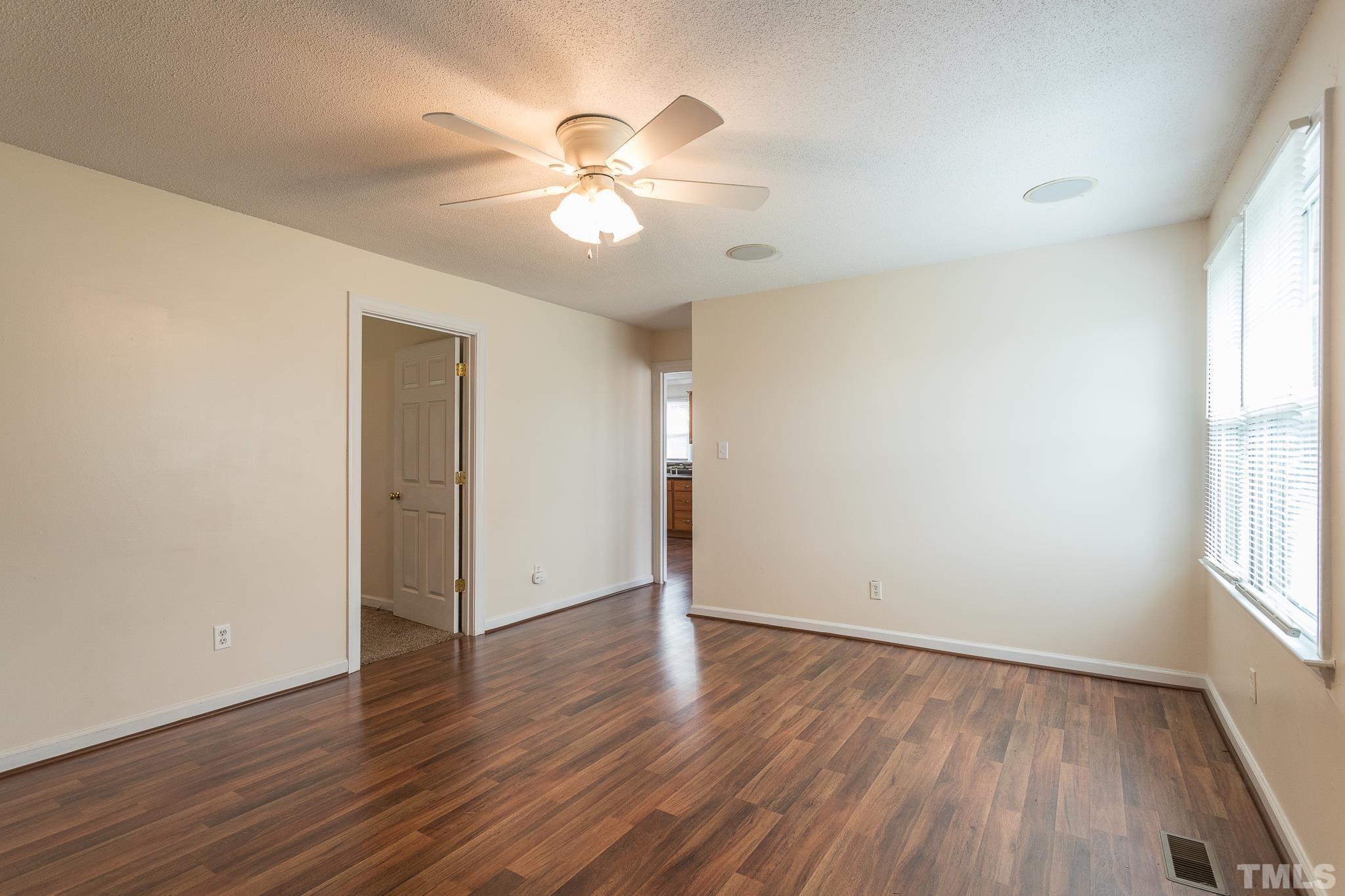 5444 Raleigh Road Benson, NC 27504 - Photo 3 of 13 an empty room with wooden floor chandelier fan and windows