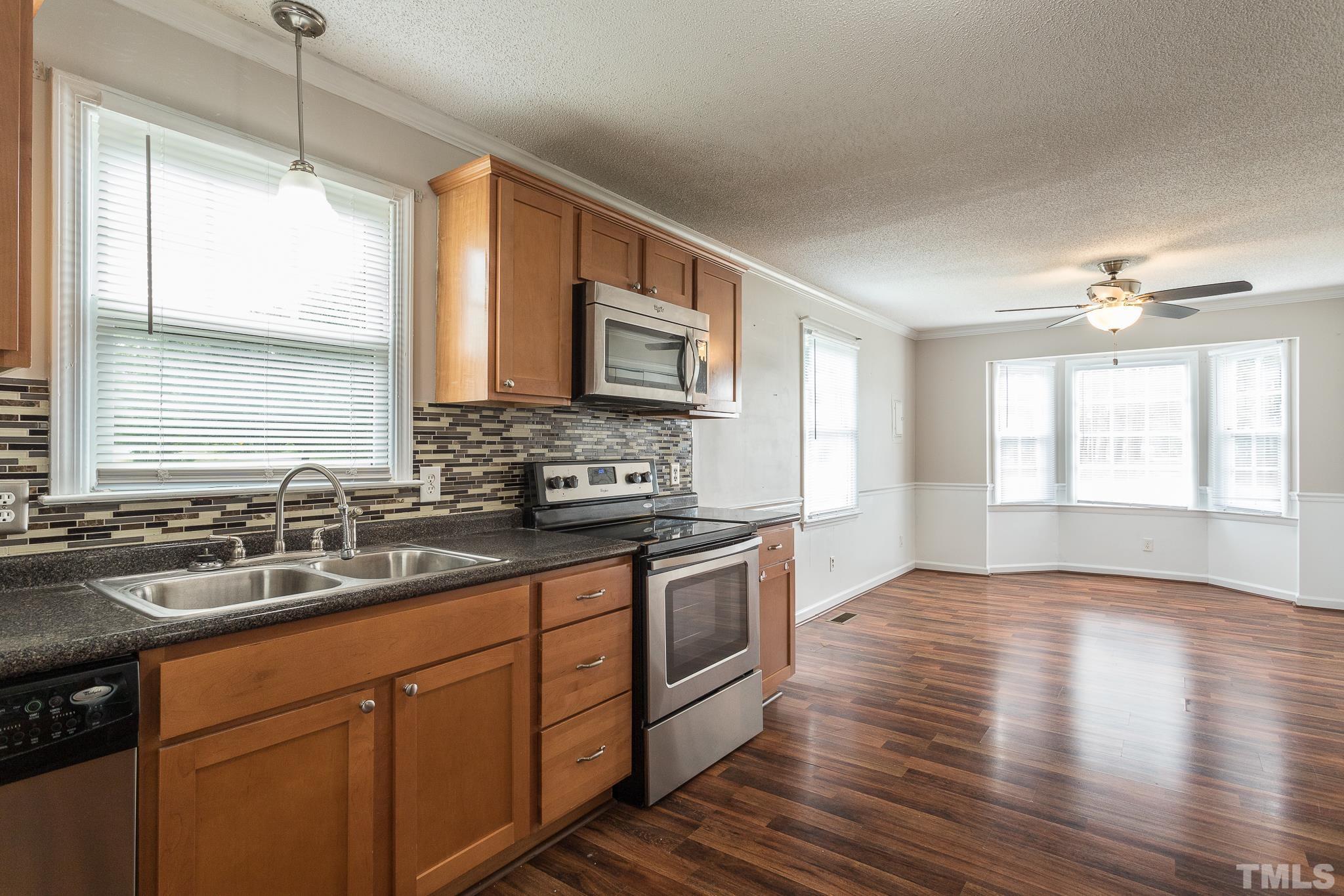 5444 Raleigh Road Benson, NC 27504 - Photo 4 of 13 a kitchen with stainless steel appliances granite countertop wooden floors wooden cabinets a sink a window and a counter space