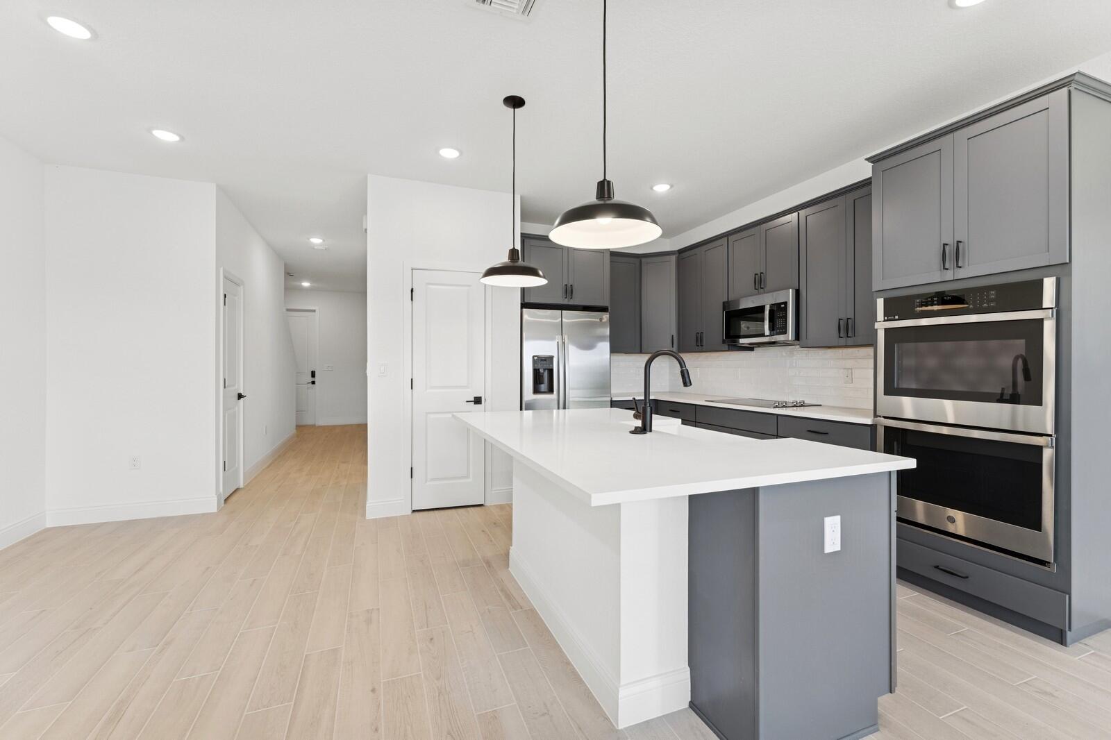 121 Southeast Birch Terrace, Unit 1157 Stuart, FL 34997 - Photo 8 of 34 a kitchen with kitchen island a sink stainless steel appliances and a chandelier