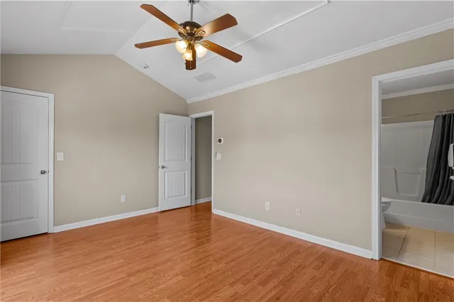 an empty room with wooden floor and ceiling fan